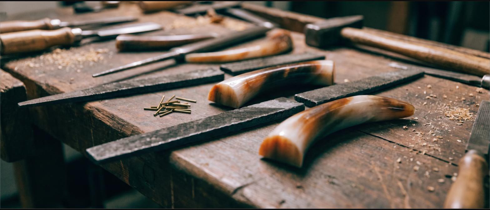 A workbench with hand files, brass pins and polished horn handle blanks
